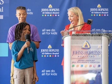 Alicia Schulhof, president of John Hopkins All Children’s Hospital, applauds for a patient and co-presenter during a groundbreaking ceremony last month.